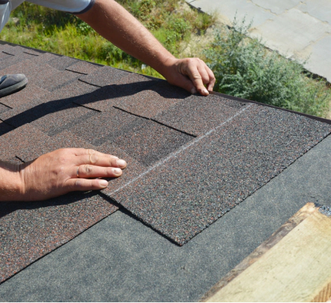 roofer installing asphalt shingles on house